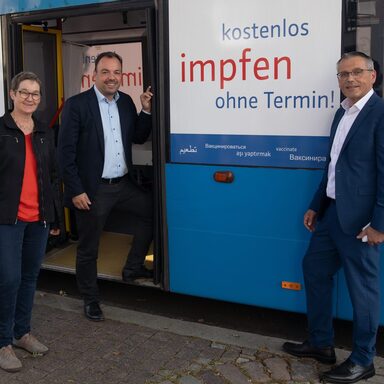Auf den Fotos sieht man die Kasseler Gesundheitsdezernentin Ulrike Gote, Oberbürgermeister Christian Geselle und Landrat Andreas Siebert vor einem Impfbus.