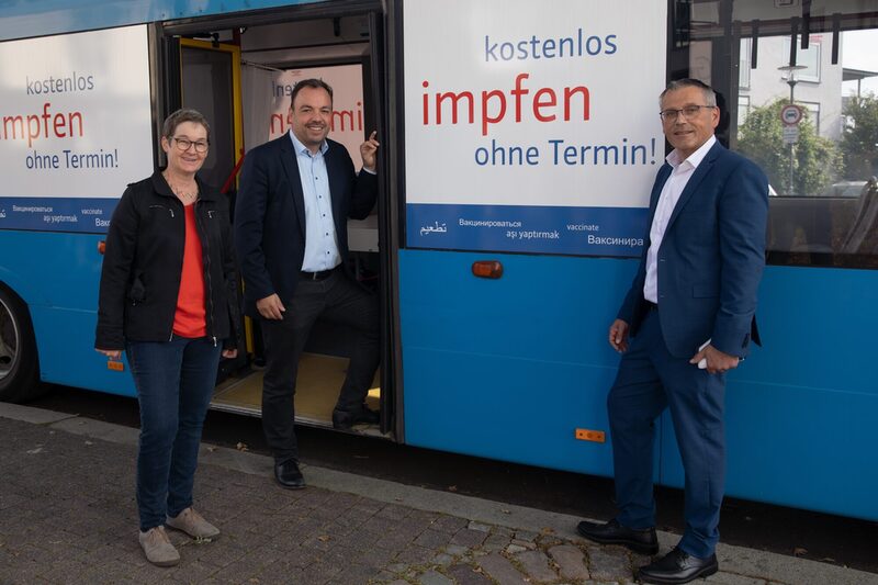 Auf den Fotos sieht man die Kasseler Gesundheitsdezernentin Ulrike Gote, Oberbürgermeister Christian Geselle und Landrat Andreas Siebert vor einem Impfbus.