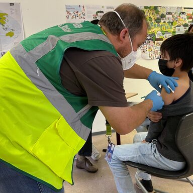 Notfallsanitäter Marc Pudenz vom mobilen Impfteam des Landkreises Kassel impft den 11-jährigen Ali aus Afghanistan.