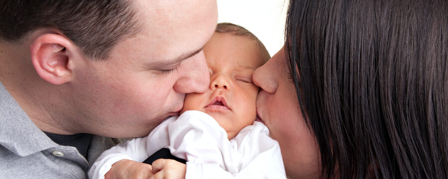 Eltern küssen die Wangen ihres Babys